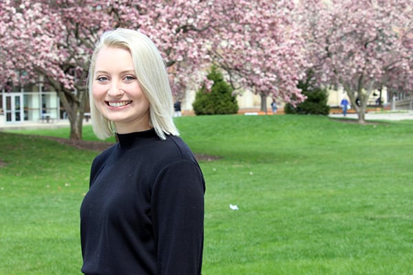 Morgan Farnworth standing in front of magnolia trees on campus