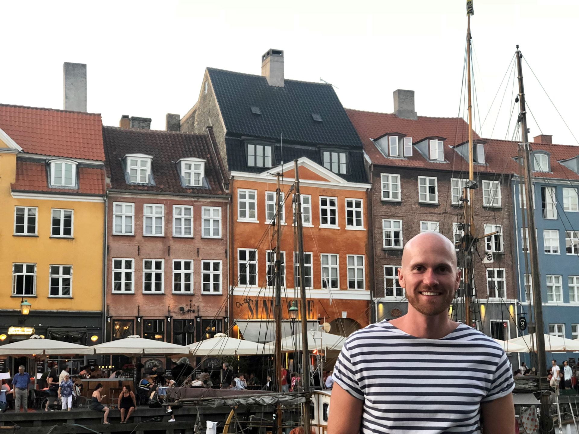 Jason Sprinkle stands in front of colorful houses in Denmark