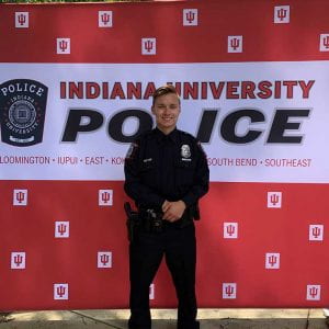man standing in front of IU police department background wearing a police uniform