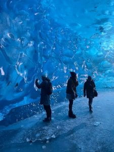 three people standing inside an ice cave