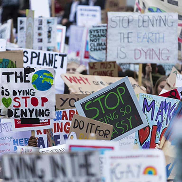 Photo of climate protest with lots of protest signs