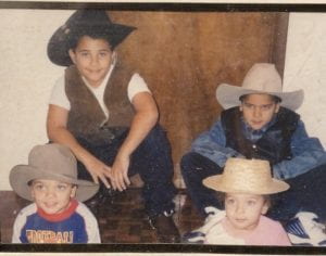 Old photo of four children wearing cowboy hats and sitting on the stairs.