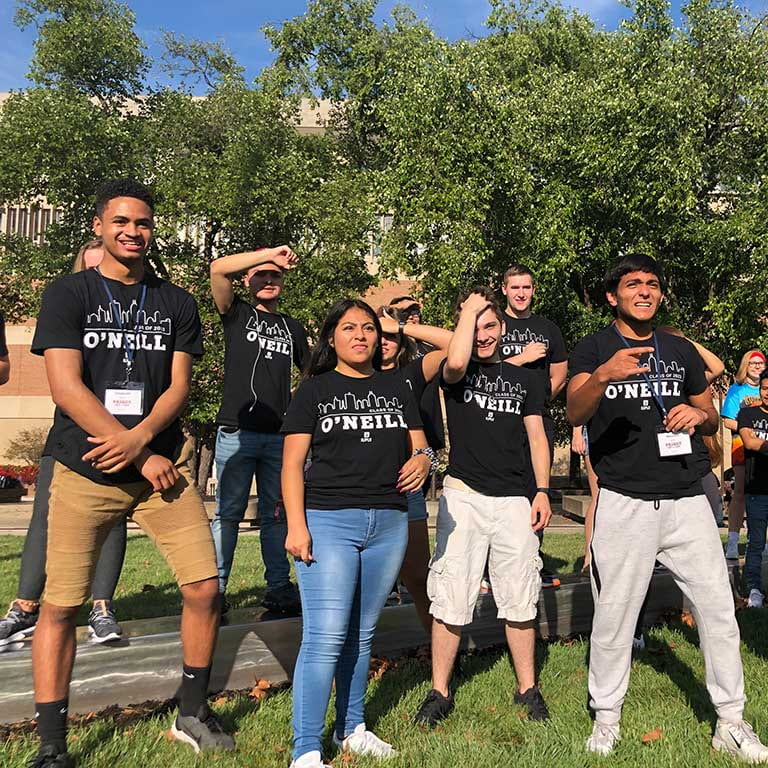 Group of students wearing Black O'Neill shirts stand in a group outside.