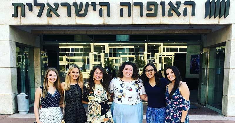 A group of women stand in front of a building in Israel during their study abroad trip.