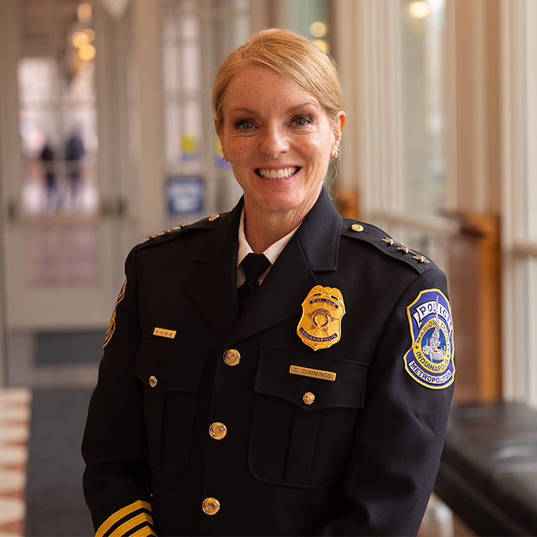 A woman in a police uniform stands in a hallway.